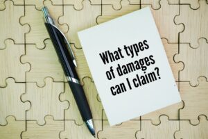 Card with the question “What types of damages can I claim?” on a wooden puzzle background with a black pen nearby.