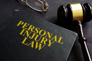 Close-up of a law book titled 'Personal Injury Law' with a wooden gavel and glasses nearby.