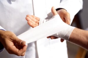 Healthcare professional wrapping a bandage around a patient’s forearm.
