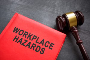 Red book titled 'WORKPLACE HAZARDS' with a wooden gavel on a dark surface.