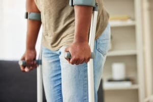 Person using forearm crutches indoors to assist mobility.